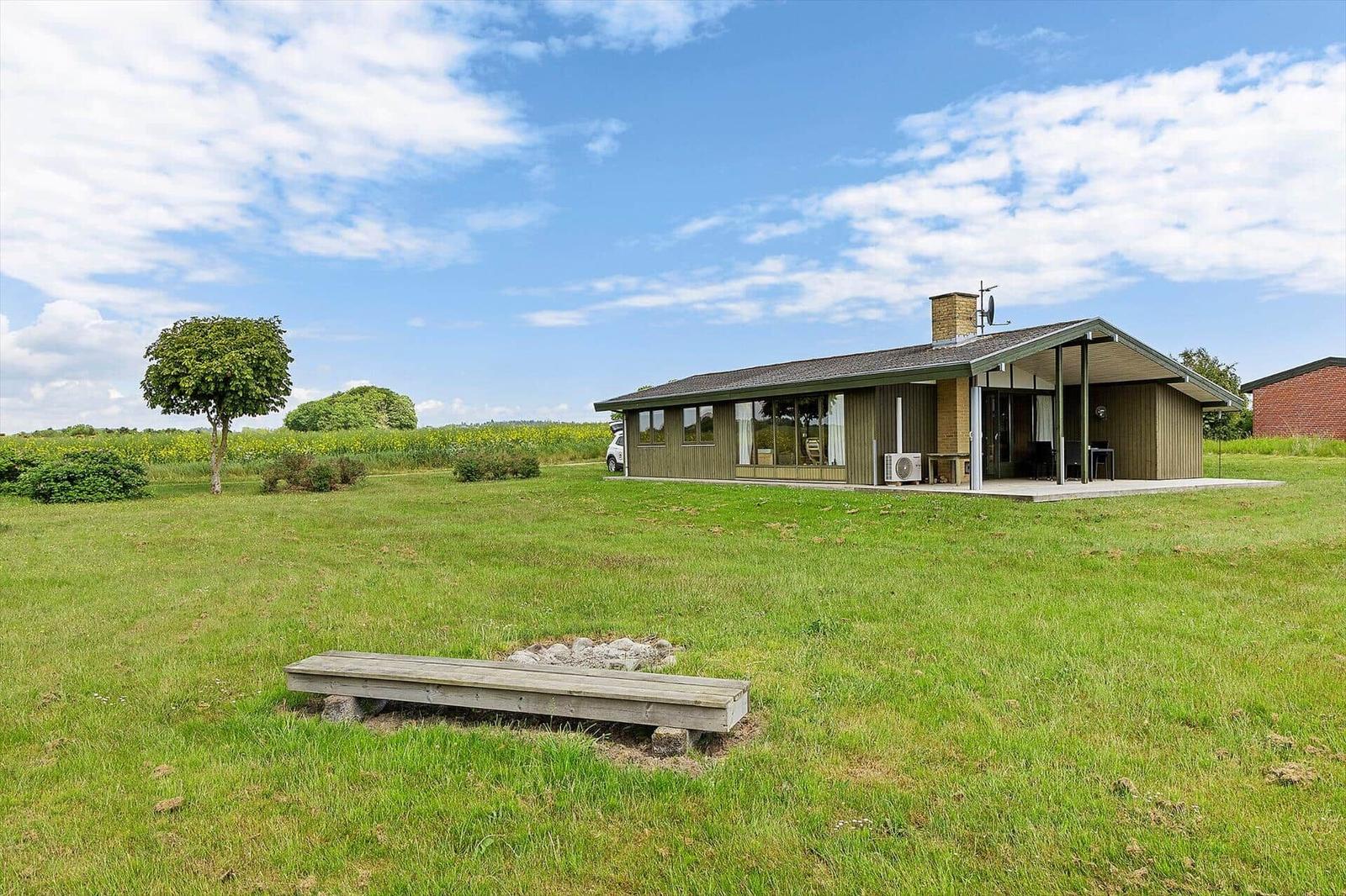 A house with a terrace stands on a green lawn under a blue sky.