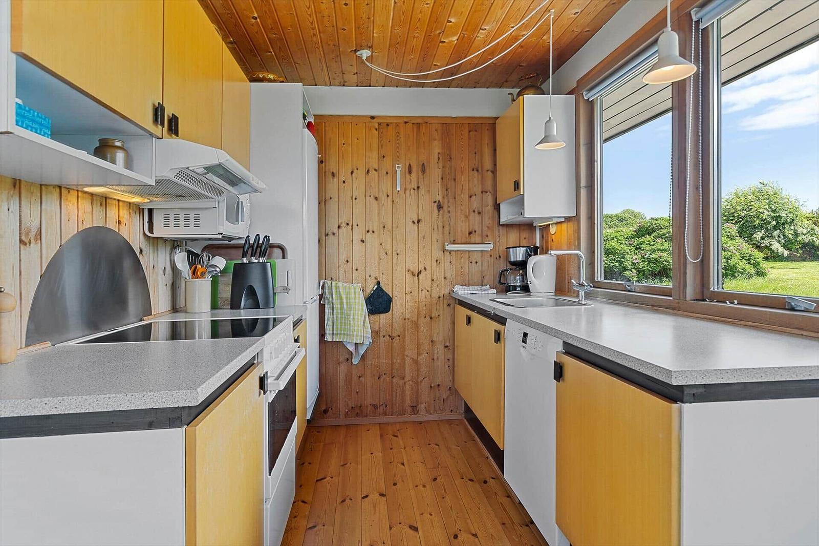 Kitchen with wooden walls, countertops, and window view of greenery.