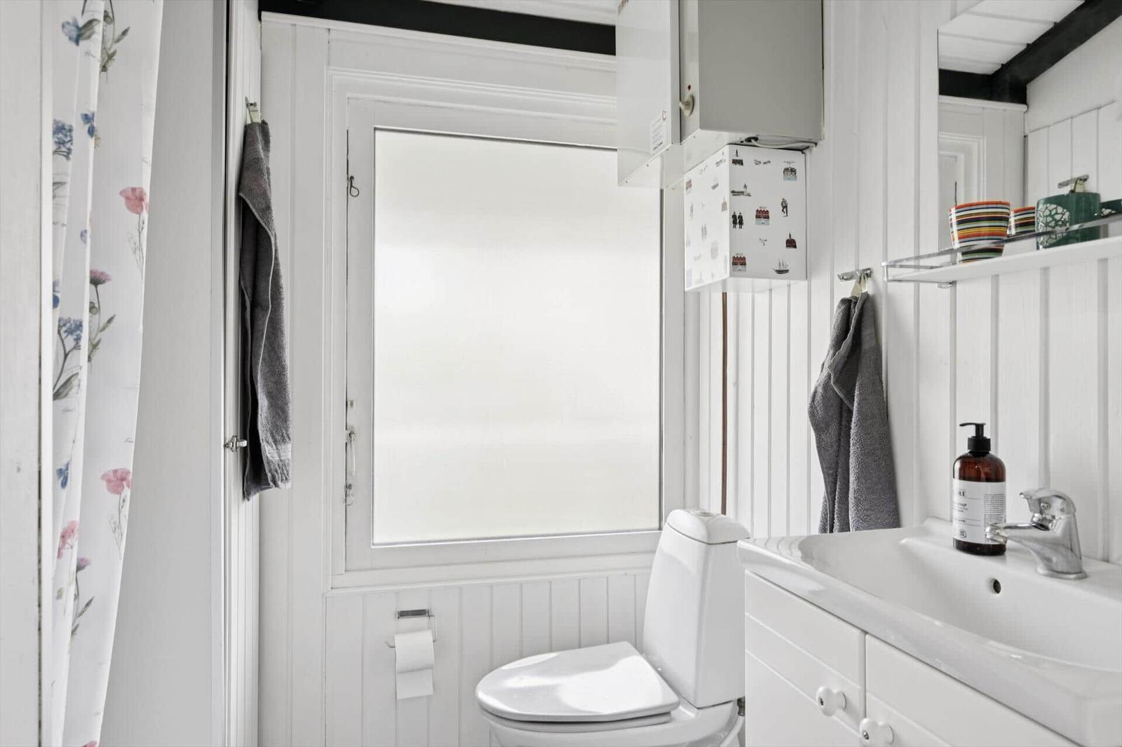 Badezimmer mit Toilette, Waschbecken und Fenster mit Milchglas.