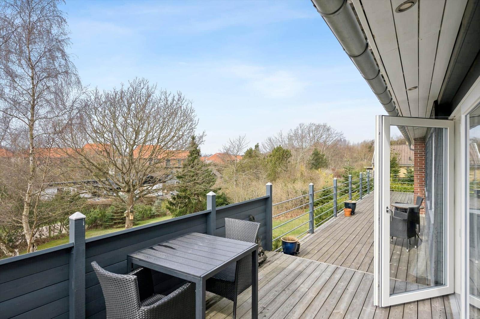 Terrasse mit Tisch und Stühlen, Blick auf Bäume und Häuser