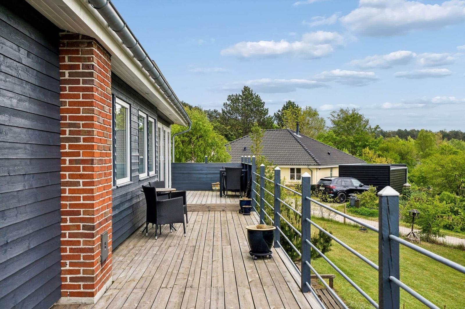 Terrasse mit Tisch und Stühlen, Blick auf grüne Landschaft und benachbarte Häuser.