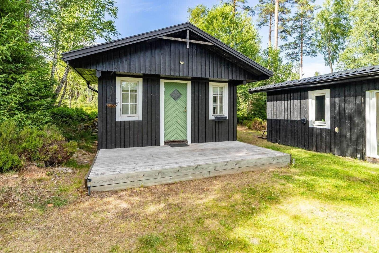 Holzhütte mit grüner Tür und Holzterrasse im Wald