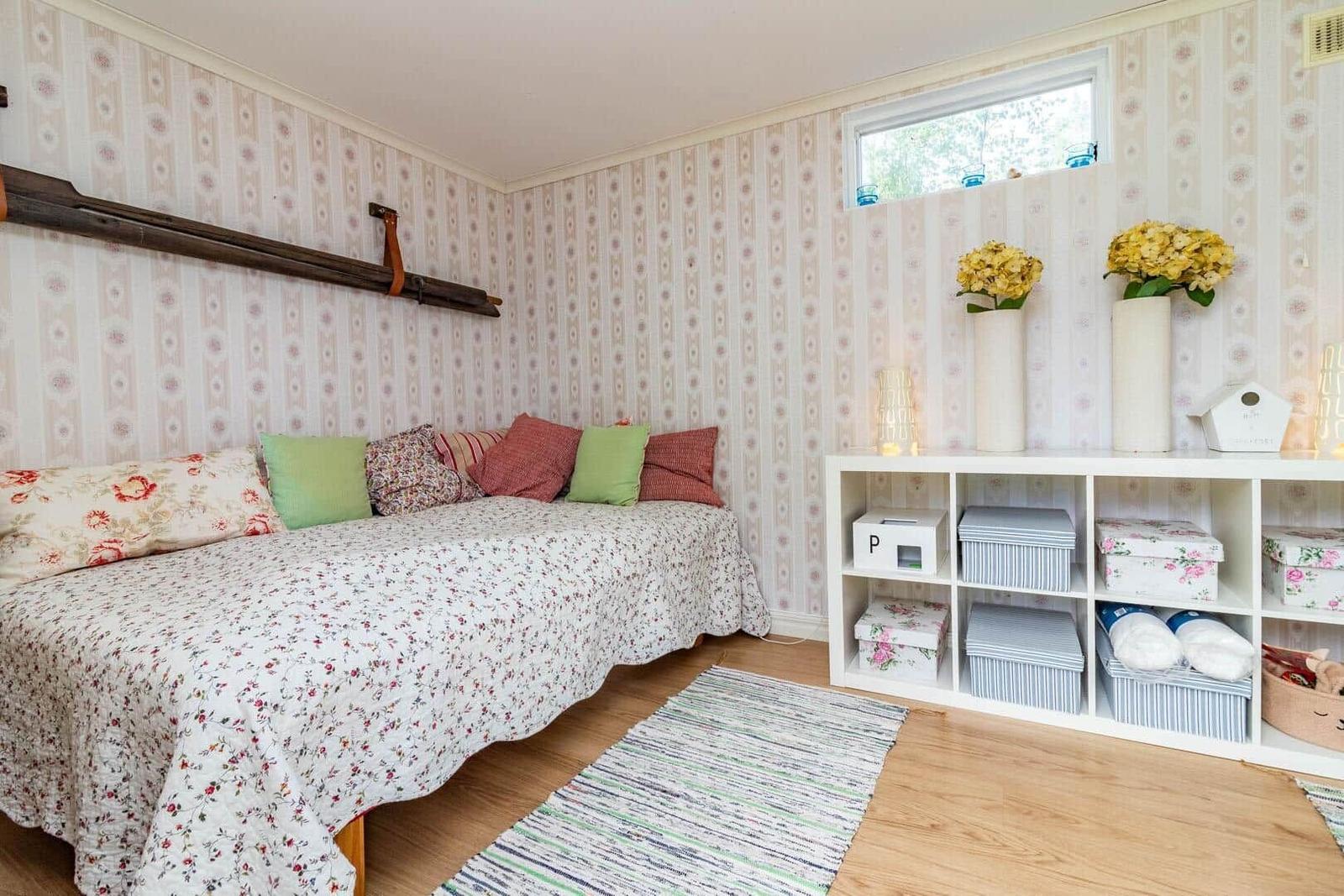 Schlafzimmer mit Bett, Wandpapier und Regal mit Aufbewahrung.