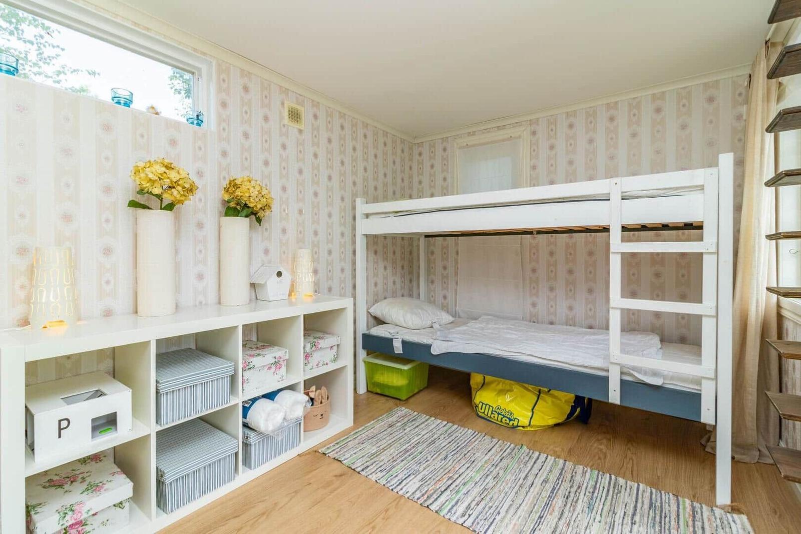 Ein Raum mit Doppelstockbett, Holzboden und Regal mit Aufbewahrung.