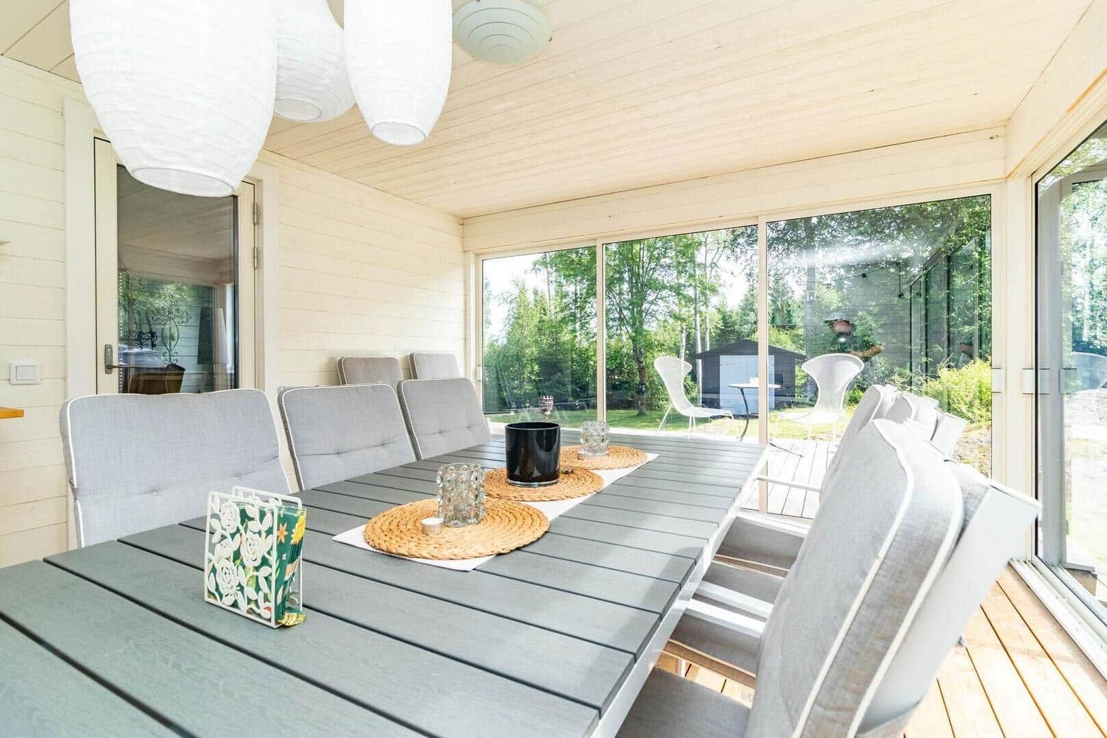 Grosser Essbereich mit Tisch und Stühlen unter einer Holzveranda mit Blick auf die Natur.