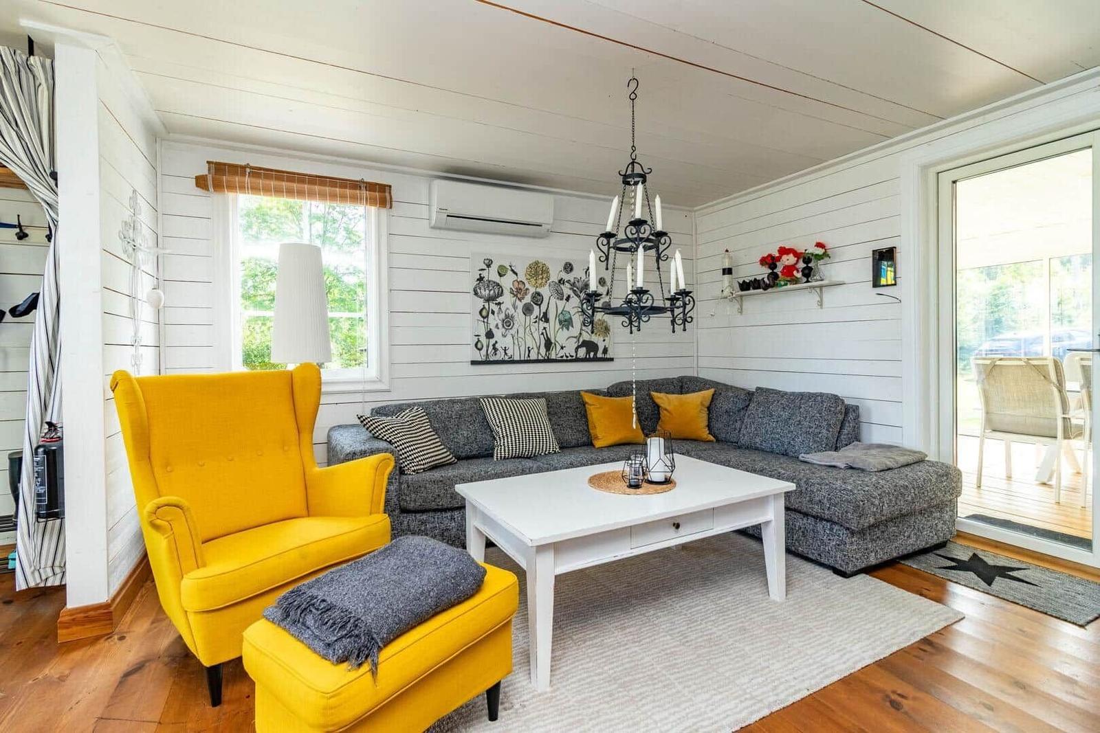 Ein Wohnzimmer mit grauem Sofa, gelbem Sessel und weißem Couchtisch.
