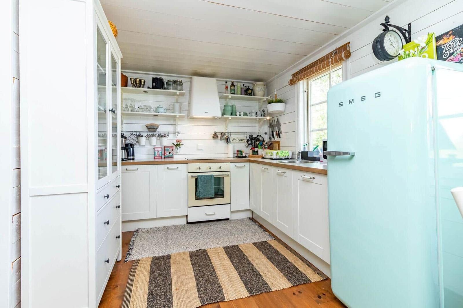 Küche mit weißen Schränken, Holzboden und hellblauem Kühlschrank.