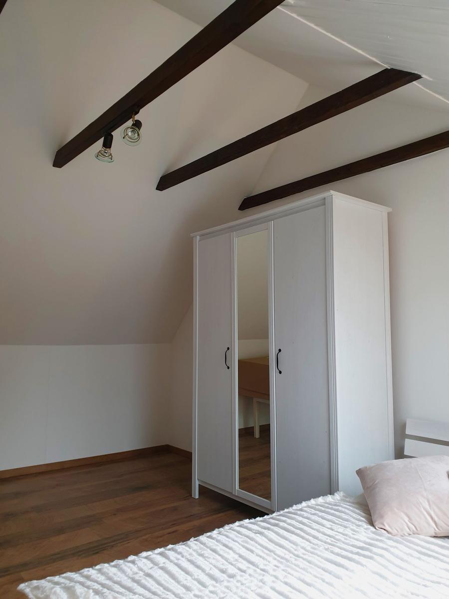 Schlafzimmer mit Dachschräge, weißem Schrank und Holzboden.
