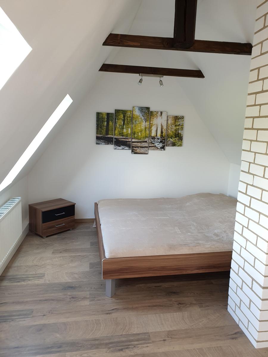 Schlafzimmer mit Dachschräge, Holzboden und Wandbild
