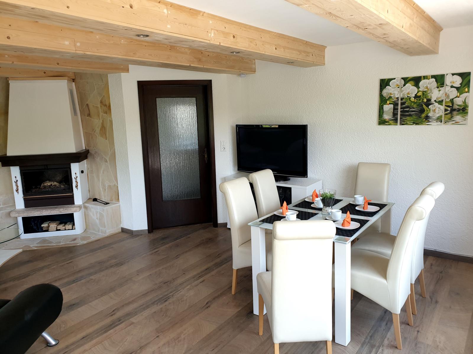 Essbereich mit Tisch und Stühlen, Fernseher und Kamin im Wohnbereich.