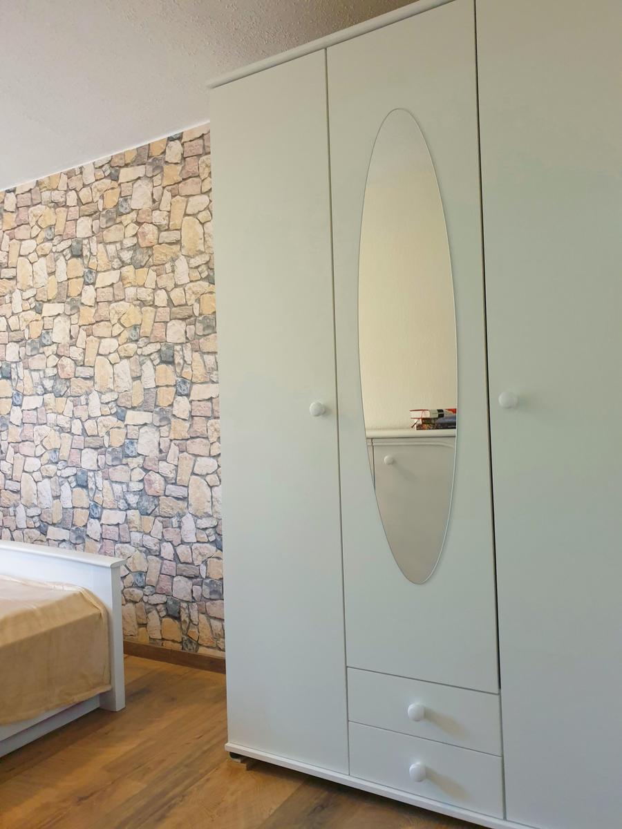Schlafzimmer mit weißem Schrank und Steinwand