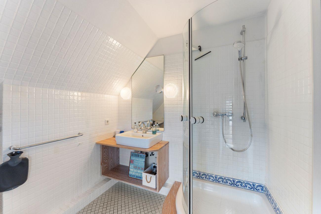 Badezimmer mit Dusche, Waschbecken und Handlauf an der Wand.