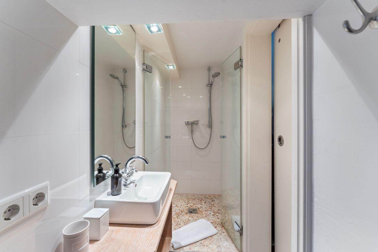 Badezimmer mit Dusche, Waschbecken und Spiegel