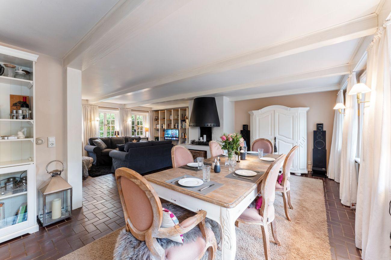 Esszimmer mit Tisch und Stühlen, Blick in Wohnbereich mit Sofa und Kamin.