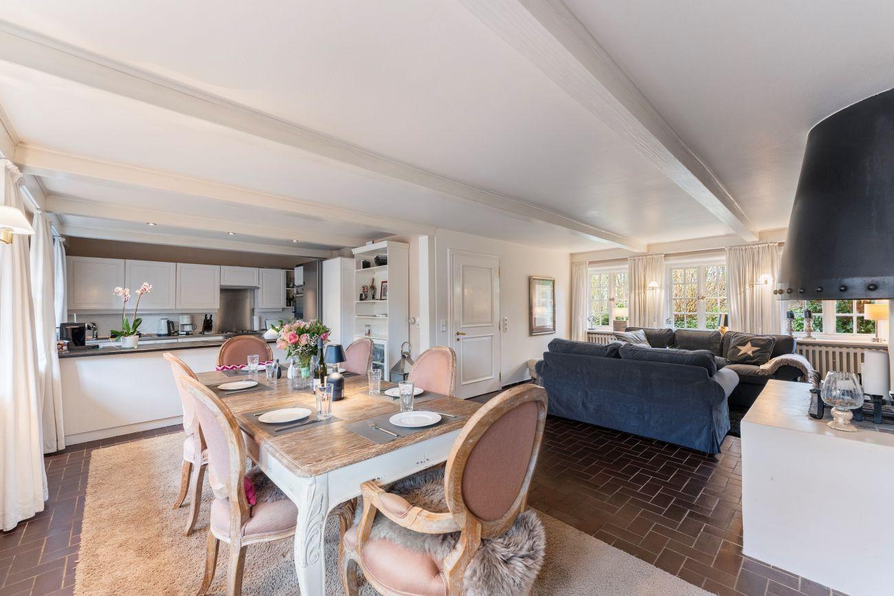Essbereich mit Tisch und Stühlen, Wohnzimmer mit Sofa, Küche im Hintergrund.