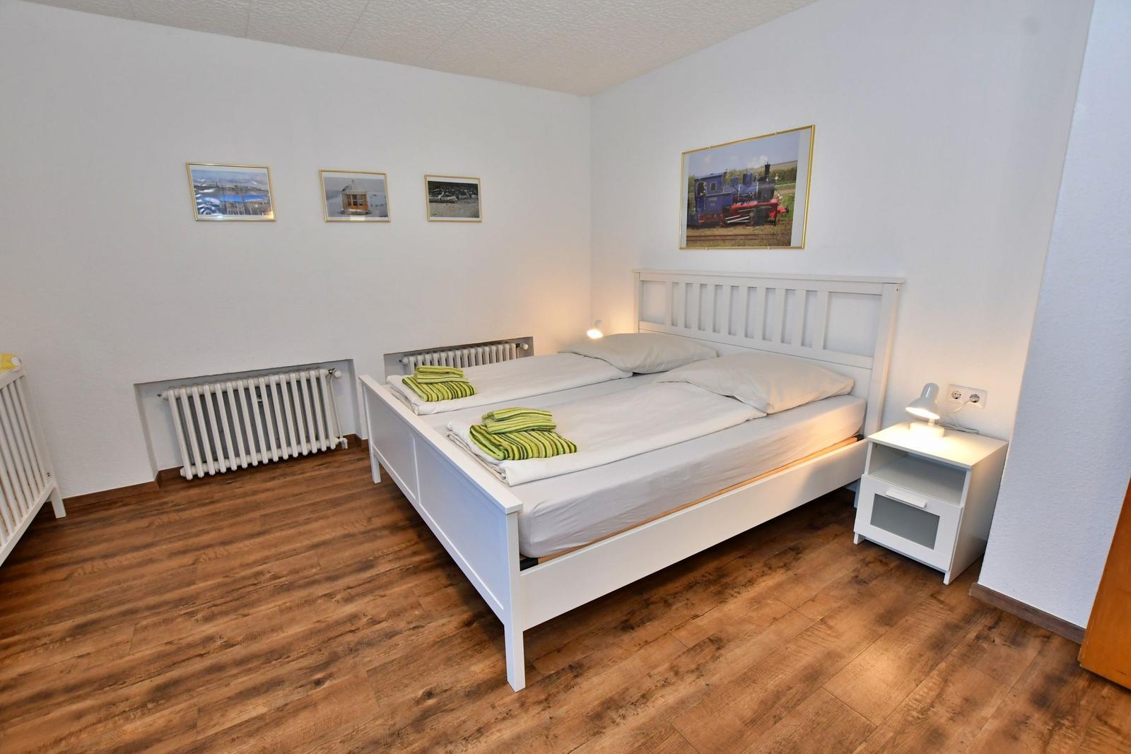 Schlafzimmer mit Doppelbett, Holzboden und Wandbildern.