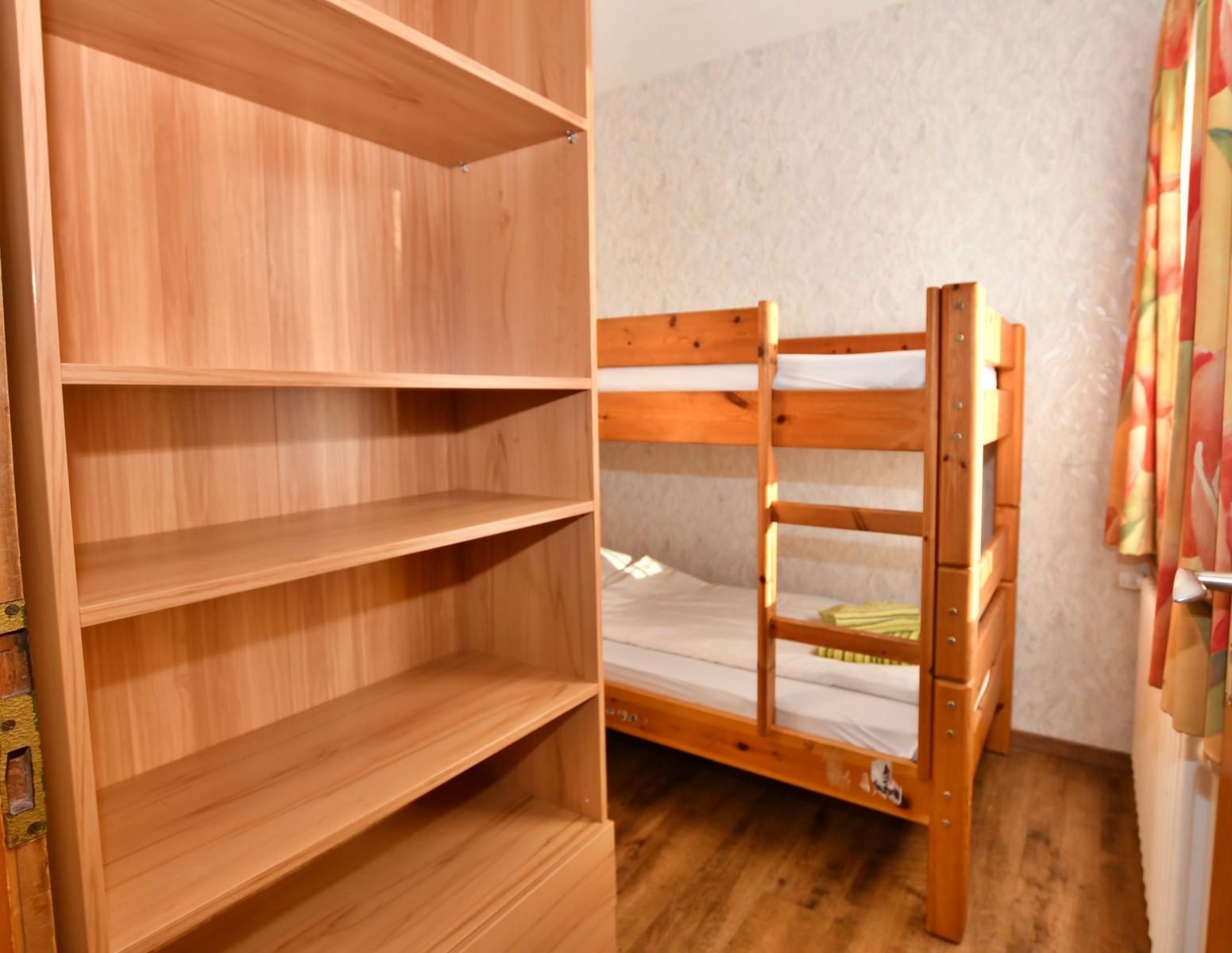Zimmer mit Holz-Etagenbett und offenen Regal