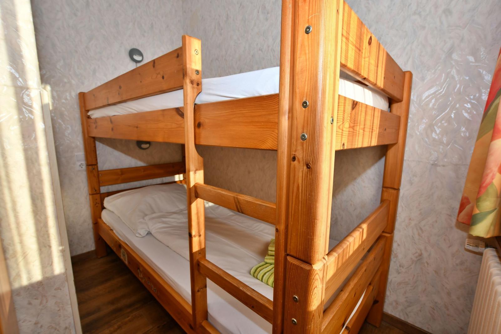 Holz-Kinderbett mit zwei Schlafplätzen und weißen Bettwäsche.