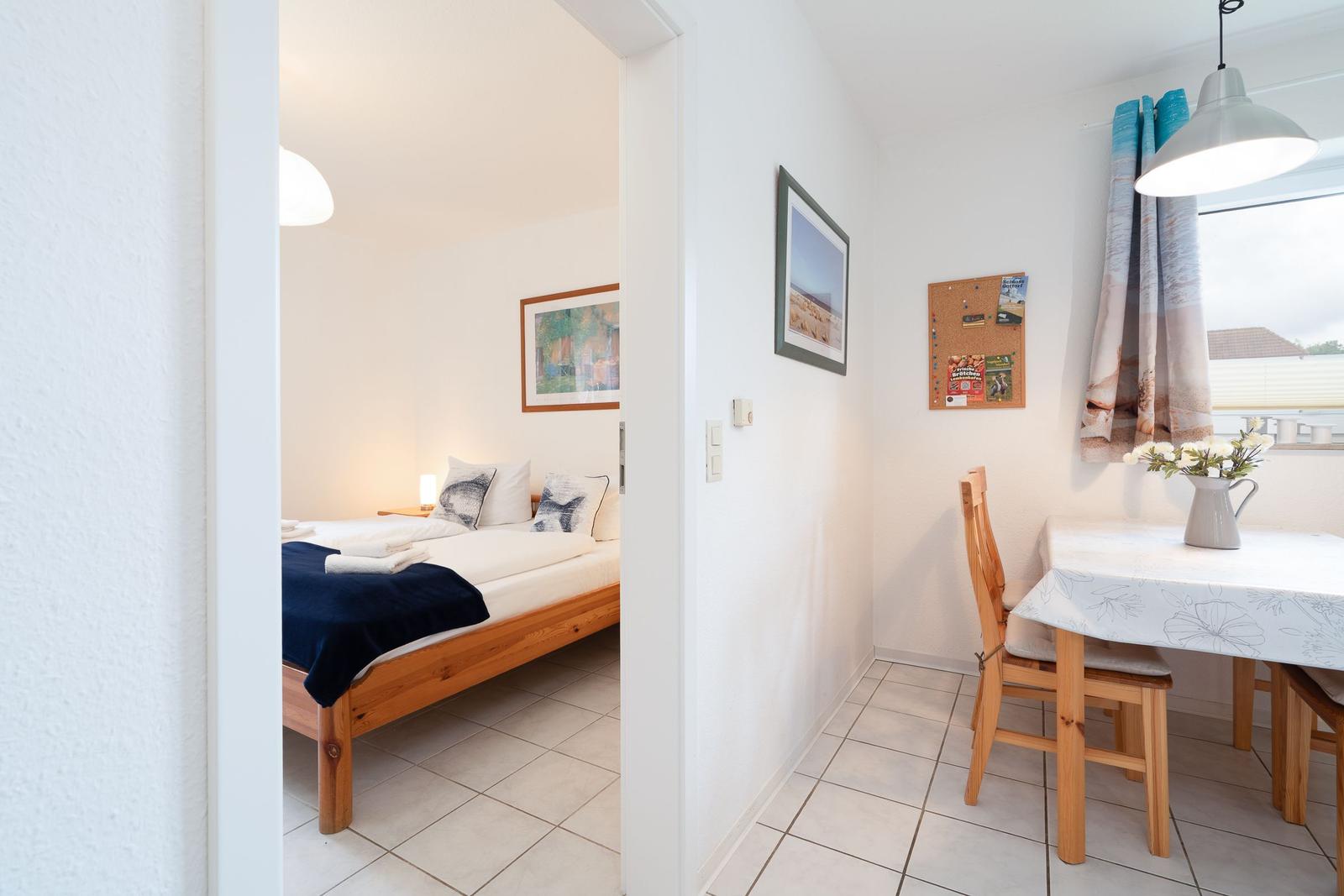 Bedroom with bed and picture. Dining area with table, chairs, and window.