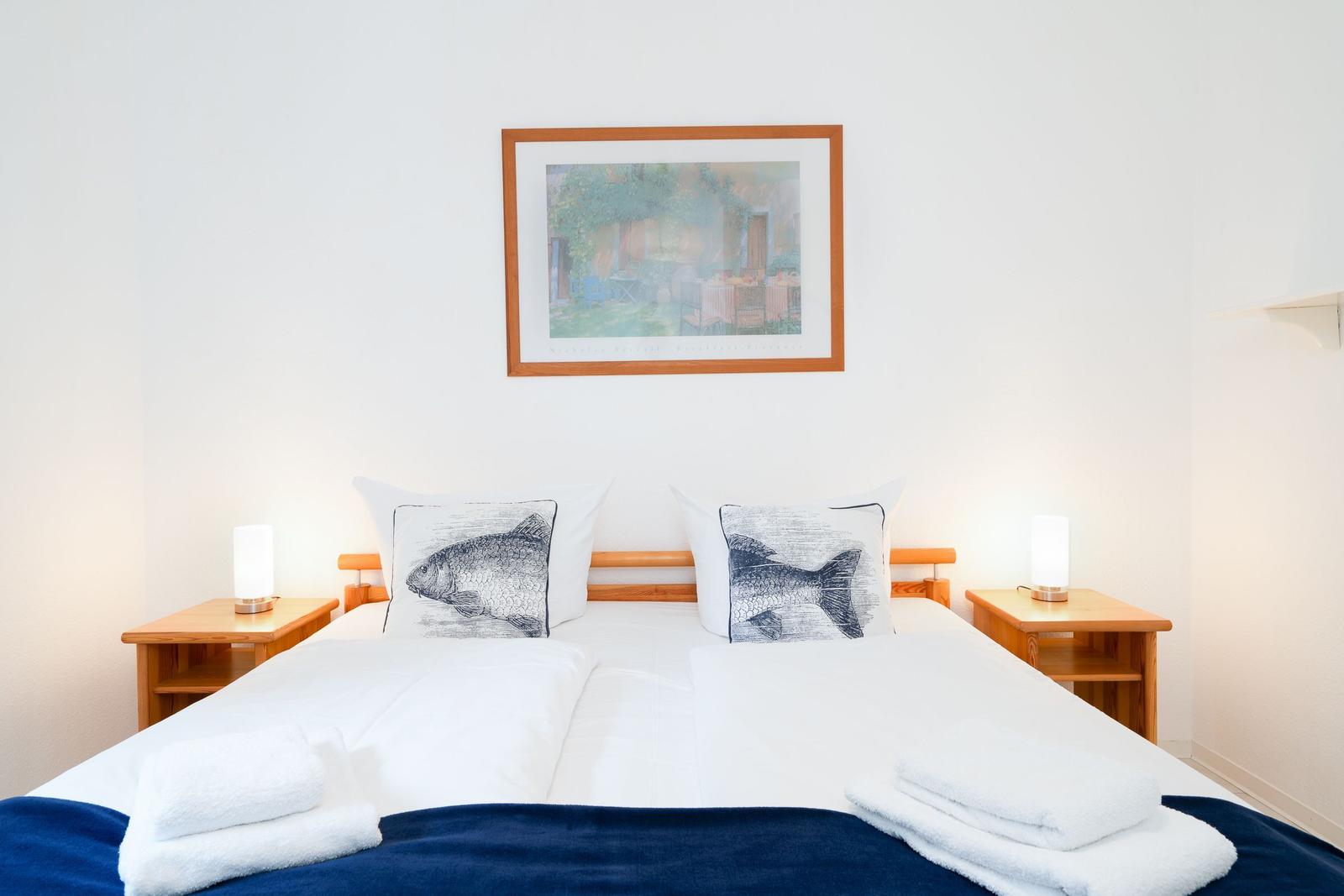 Double bed with white linens, two nightstands with lamps, and artwork above the bed.