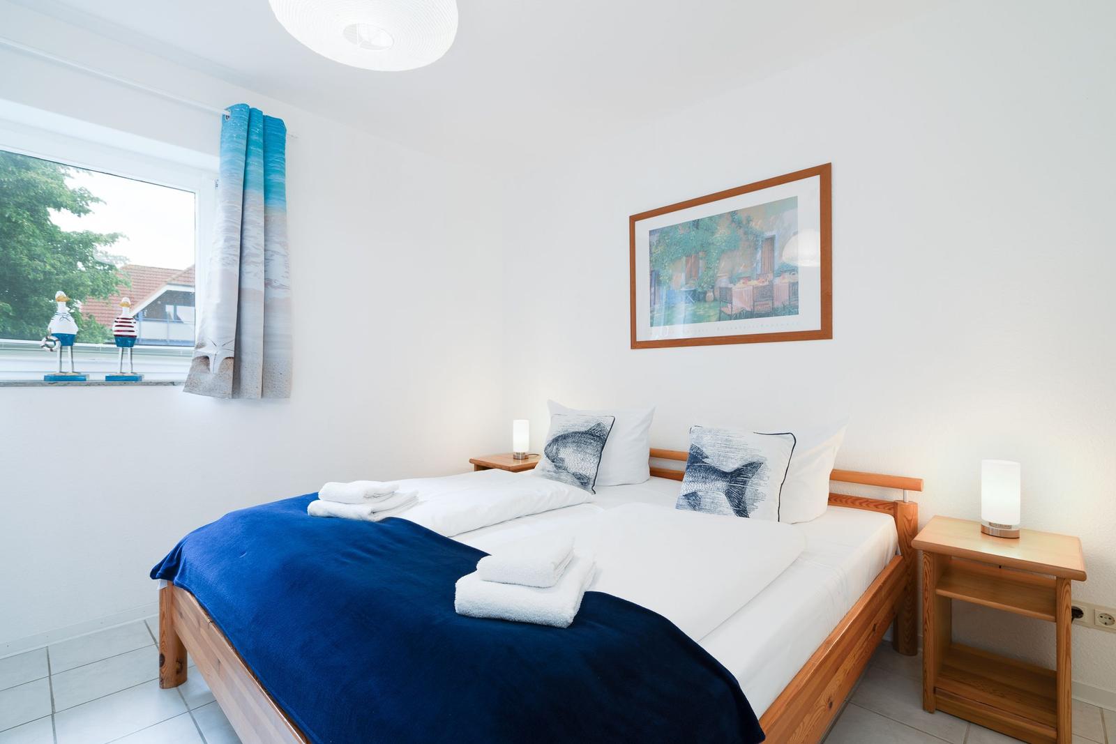 Bedroom with bed, nightstands, and window with view of outside area.