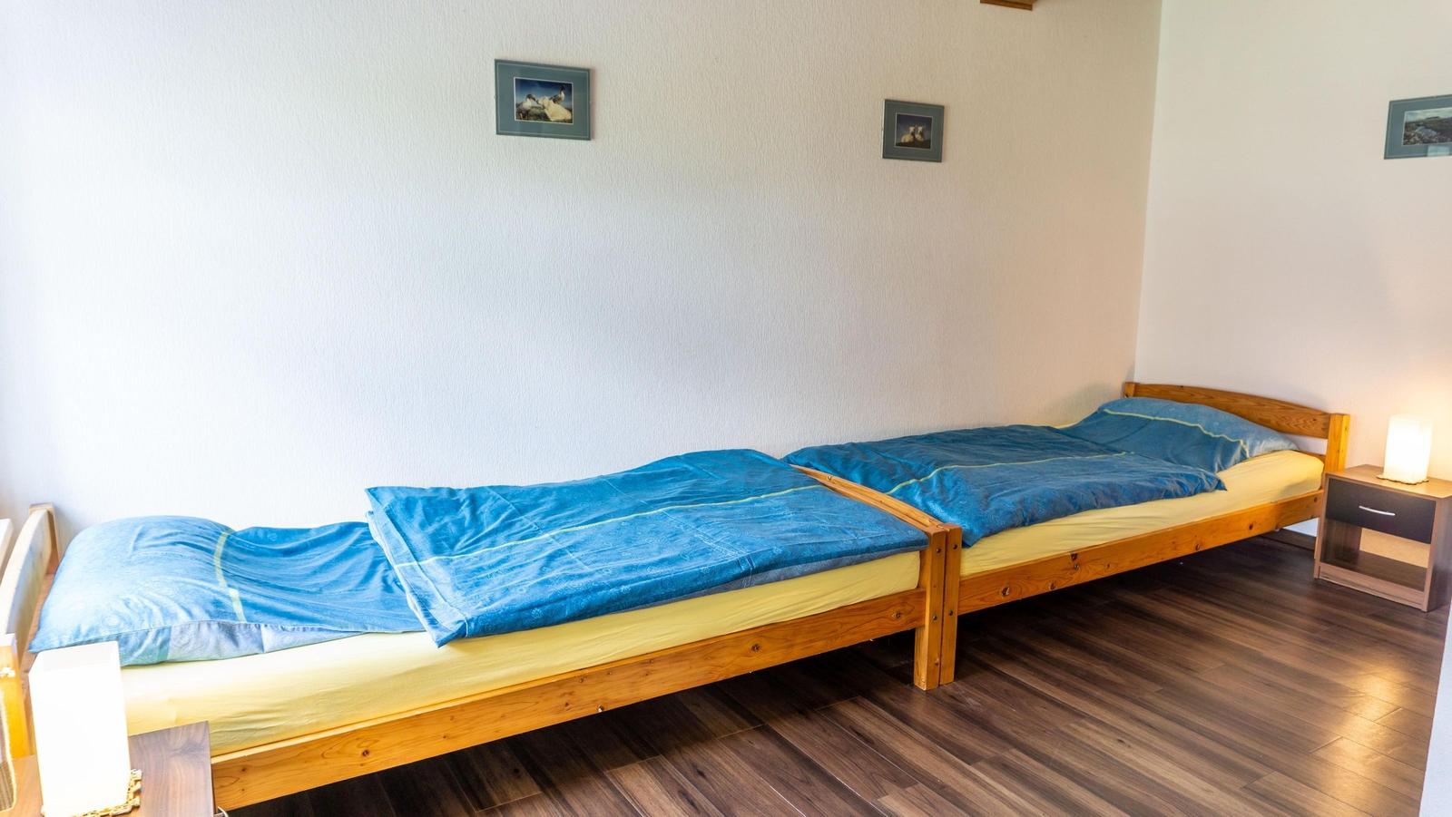 Zwei Einzelbetten mit blauen Bettwäschen und Holzrahmen stehen im Zimmer.