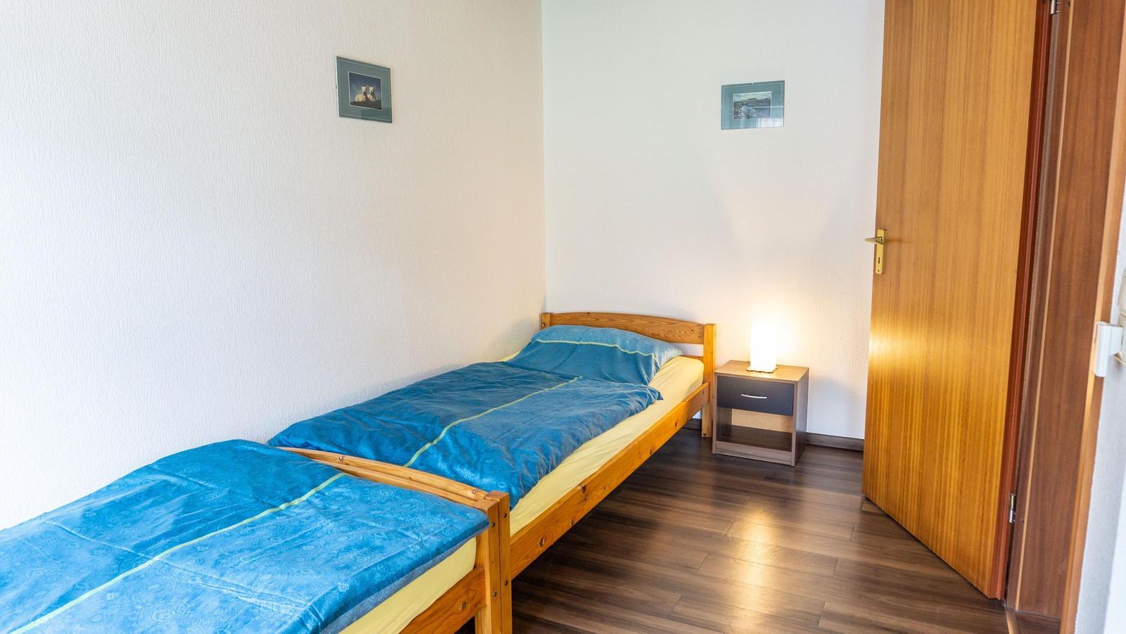Ein Schlafzimmer mit zwei Einzelbetten, Nachttisch und Tür.