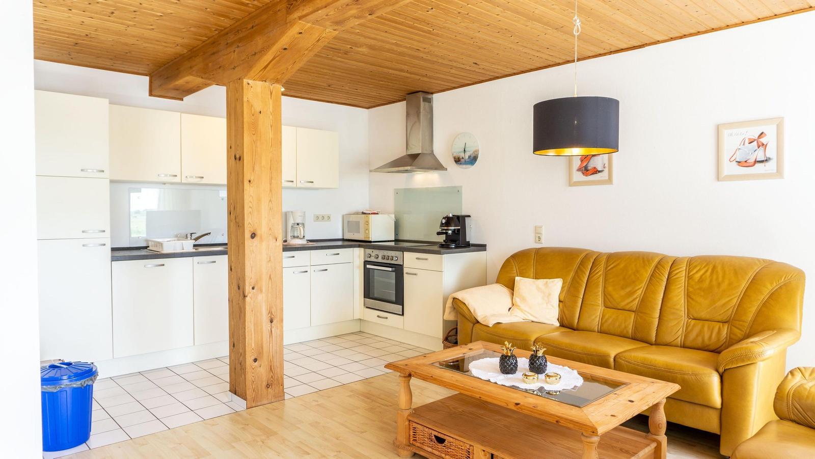 Wohn- und Küchenbereich mit Holzdecke, gelbem Sofa und Holztisch.
