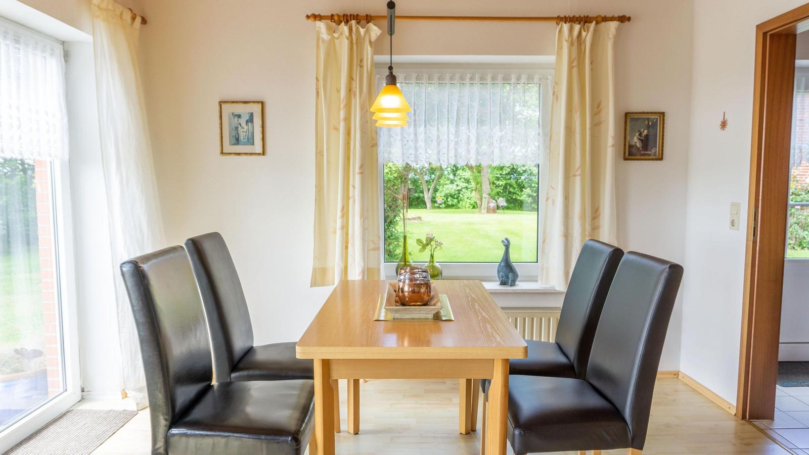 Esszimmer mit Holztisch, vier Stühlen und Blick auf den Garten.