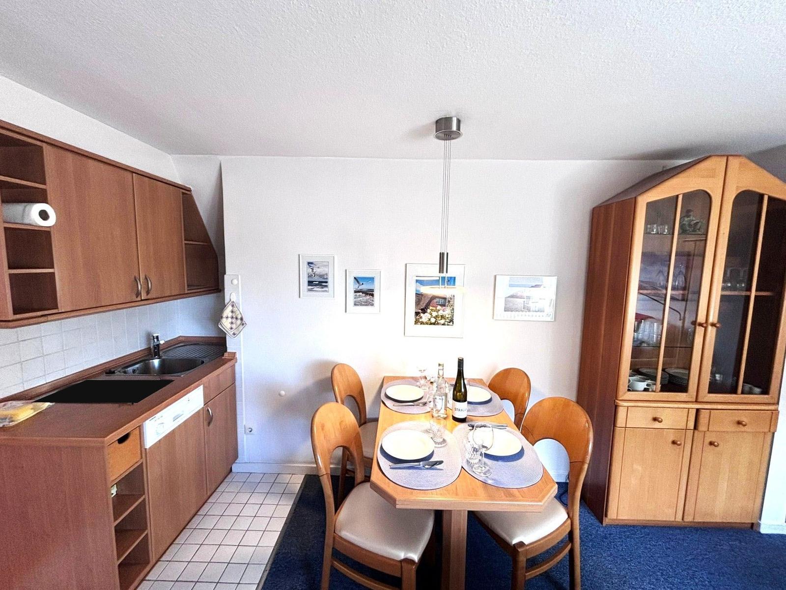 Kitchen with dining area, wooden table, chairs, hutch, and wall pictures.