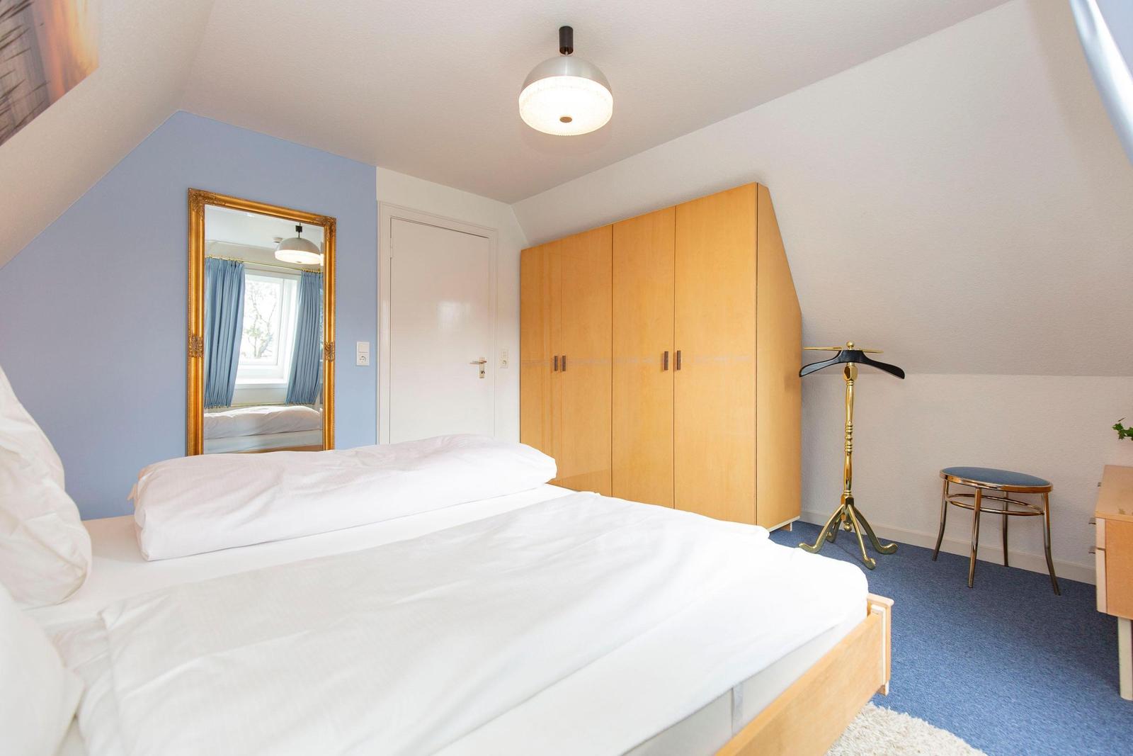 Bedroom with double bed, wardrobe, and mirror on the wall.