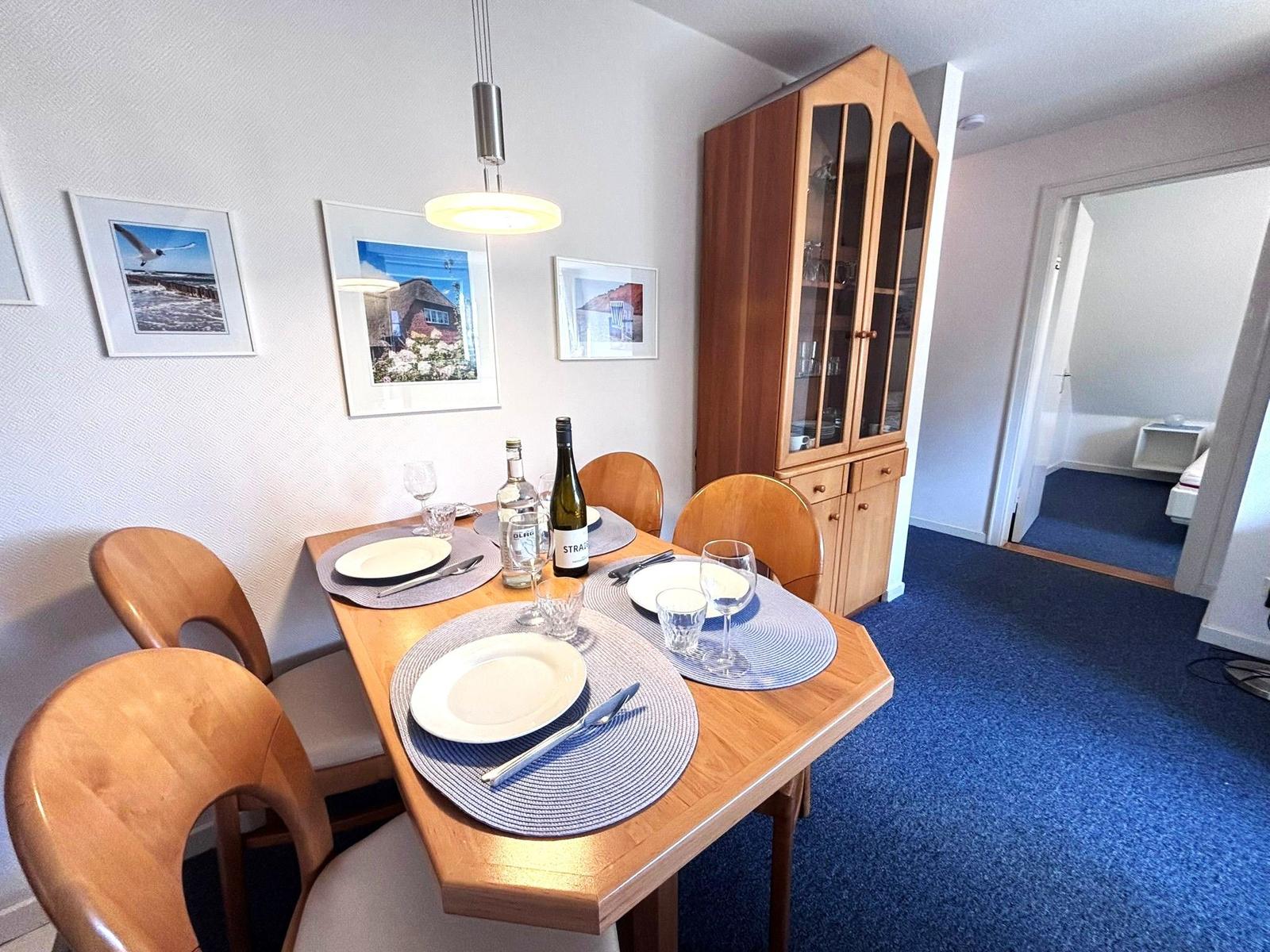 Dining table with chairs, hutch, and wall pictures. View into the bedroom.