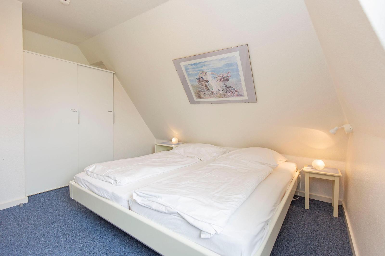 Bedroom with double bed, wardrobe, and nightstand under sloped walls.