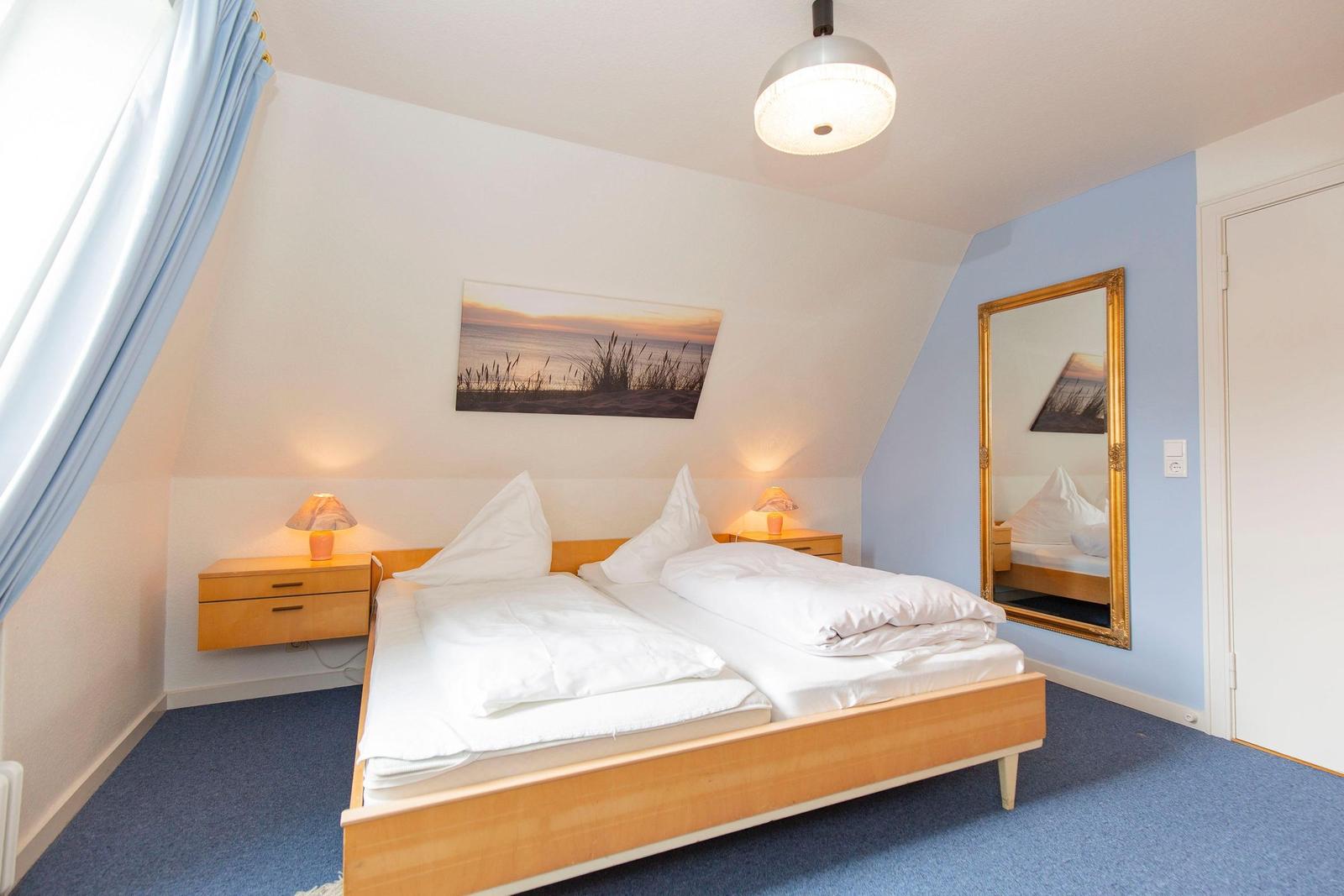 Bedroom with double bed, two nightstands, and mirror on the wall.