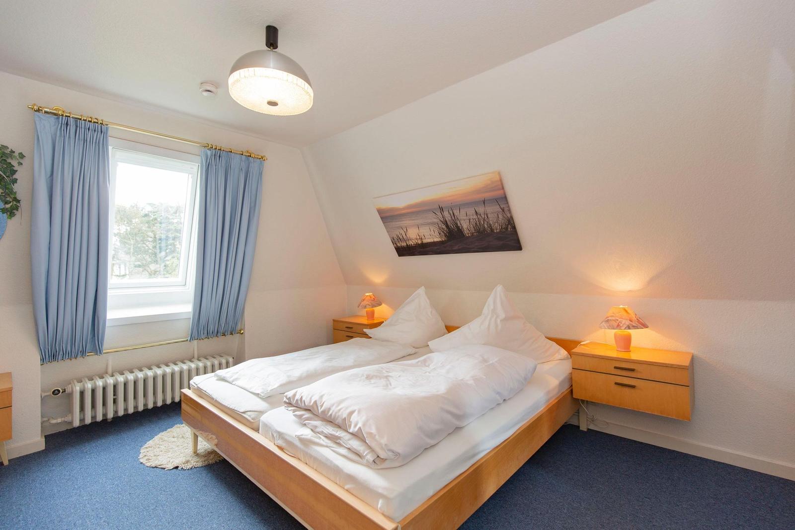 Bedroom with double bed, two nightstands, and window with blue curtains.