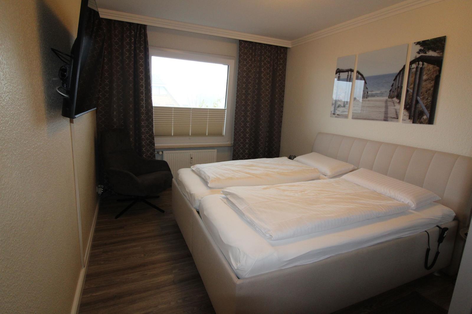 Bedroom with double bed, window, TV, and wall art
