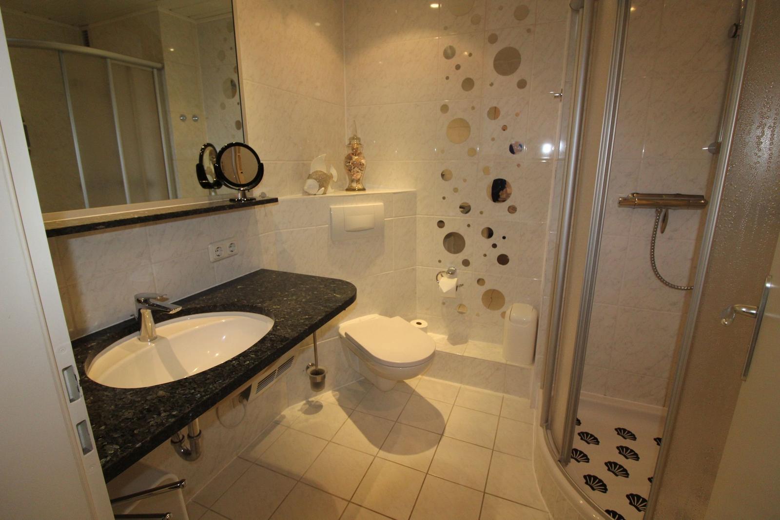 Bathroom with shower, sink, and toilet. Tiles with pattern.