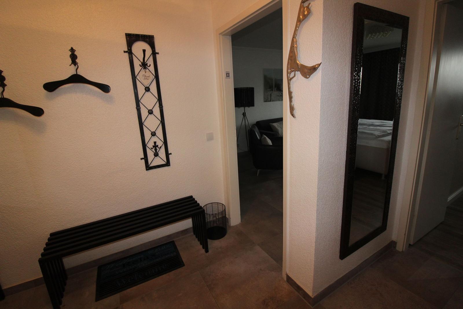 Entryway with wall coat rack, bench, and mirror. View into living and sleeping areas.