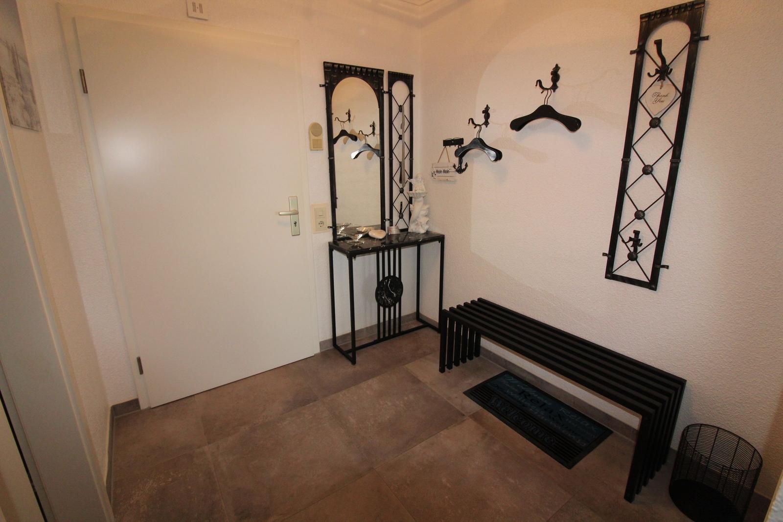 Entrance area with bench, mirror, and coat hooks on the wall.
