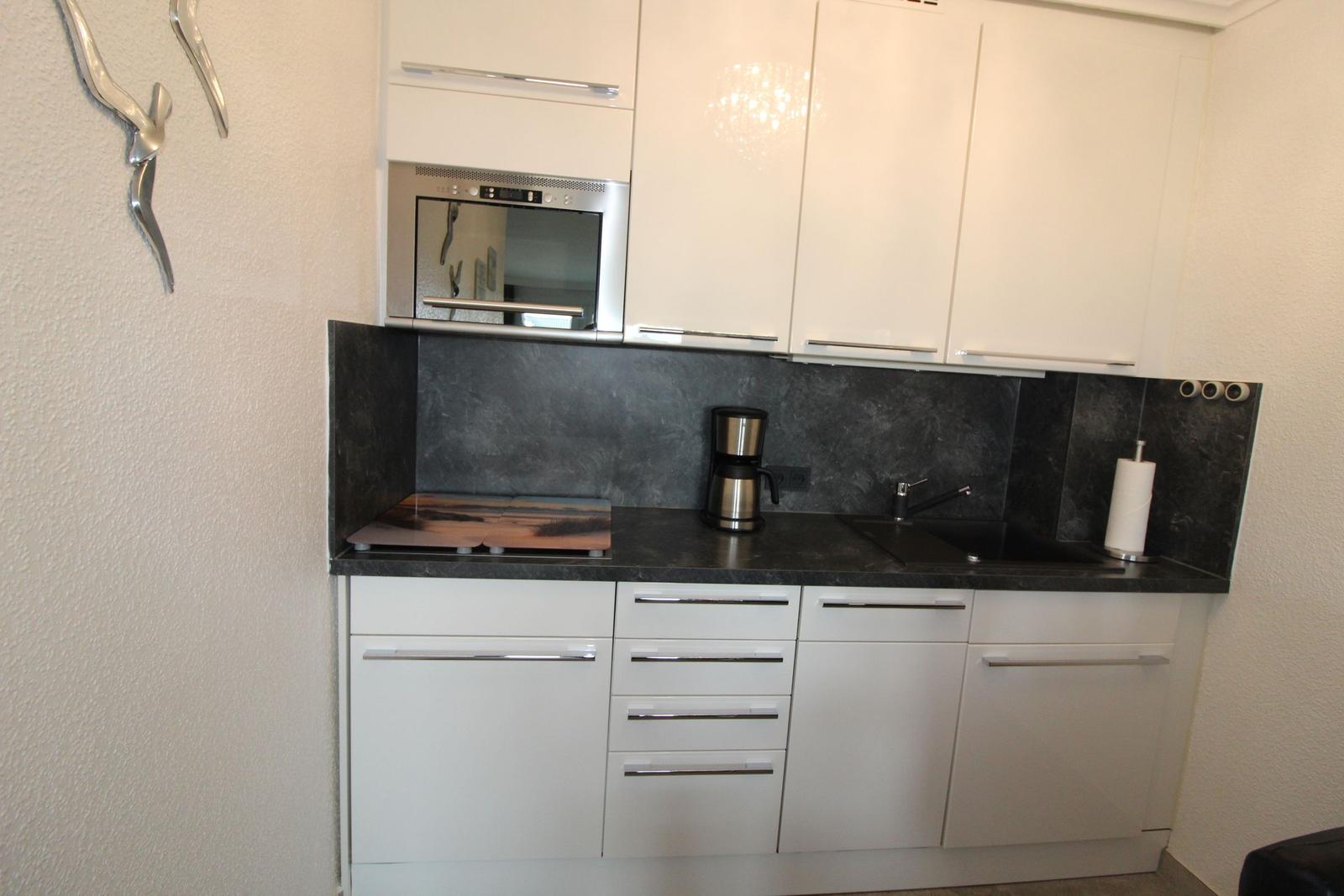 Kitchen with white cabinets, black countertop, and built-in oven.