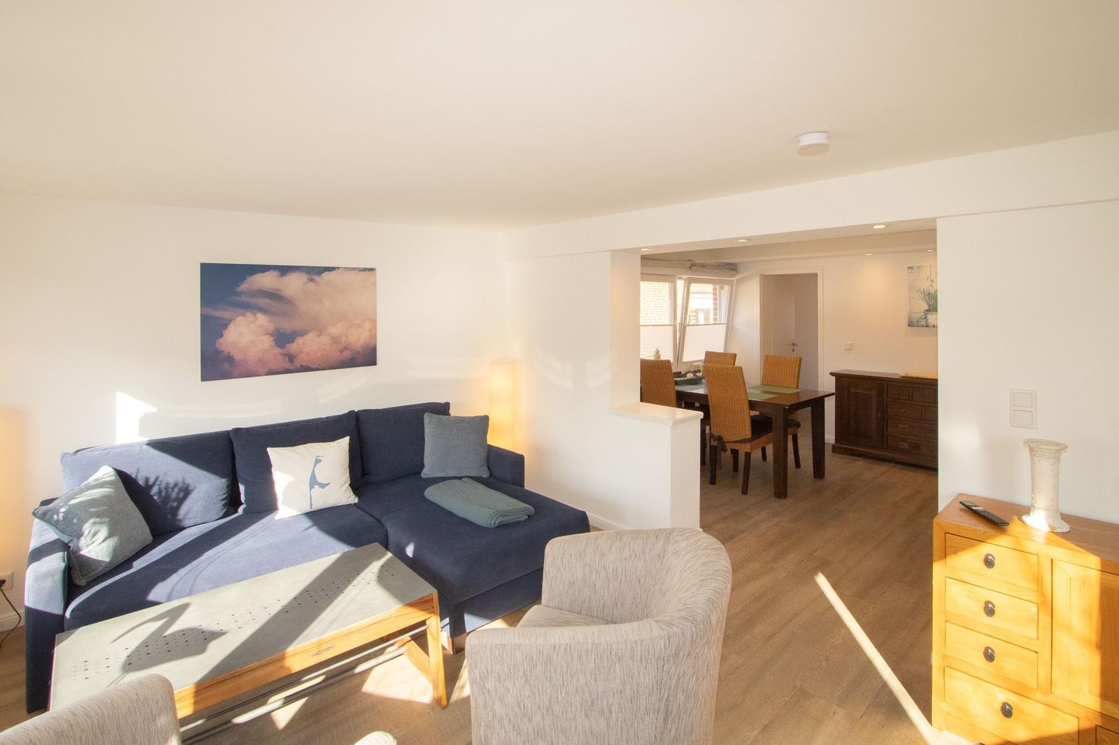 Wohnzimmer mit Sofa, Sessel und Esstisch im Hintergrund.
