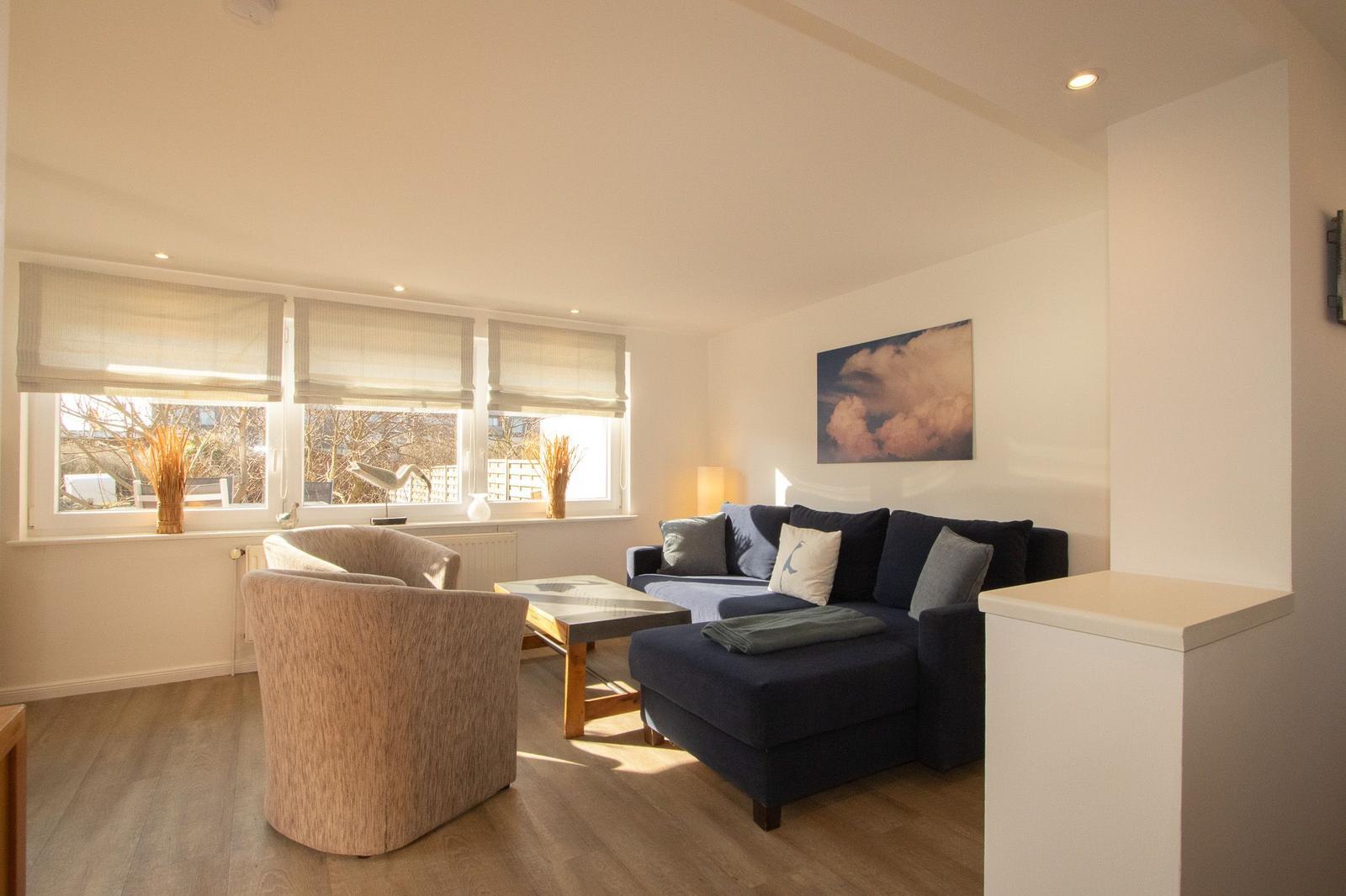 Wohnzimmer mit Sofa, Sessel und Fenster mit Jalousien.