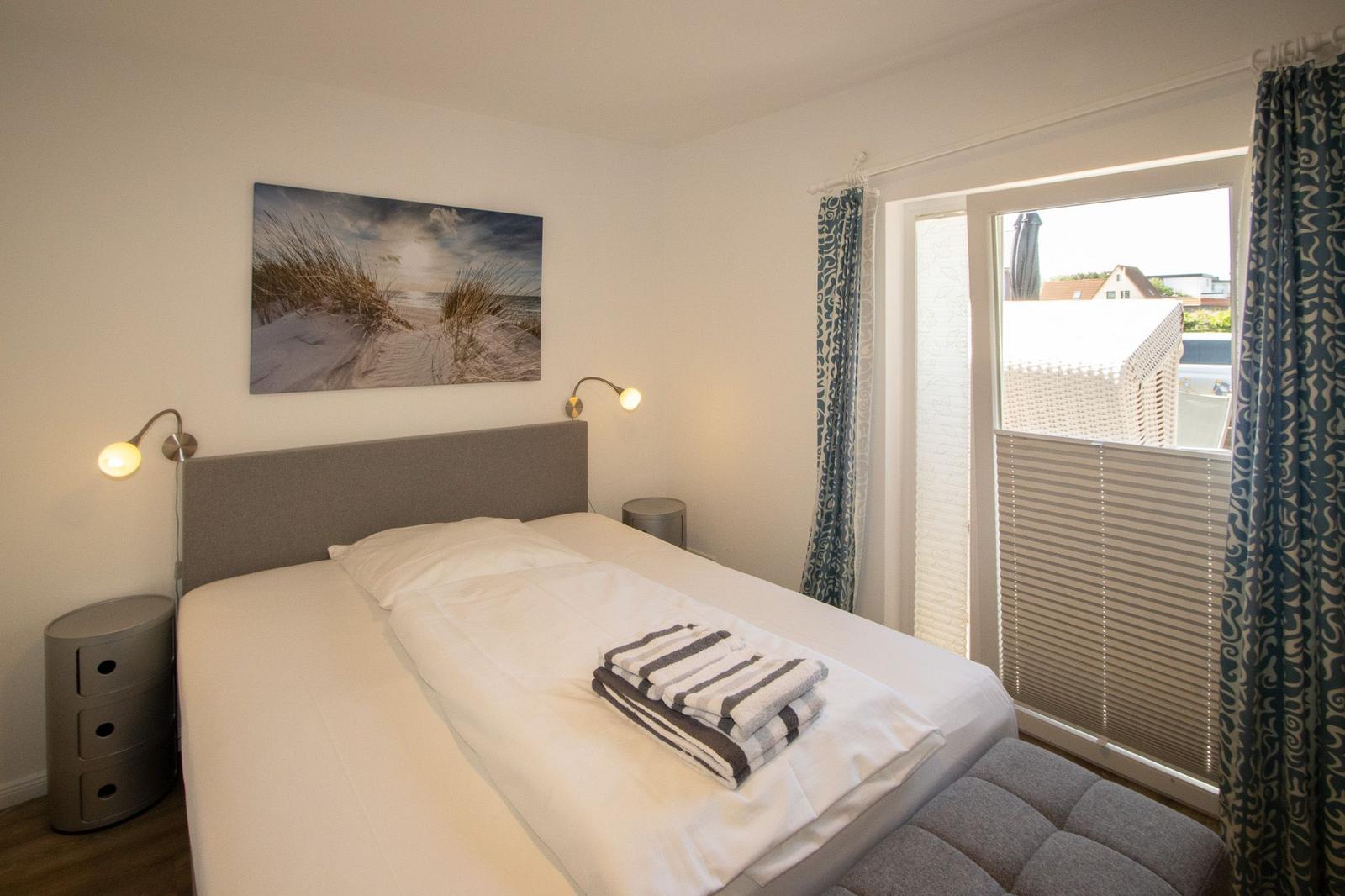 Bedroom with bed, wall art, and balcony view.