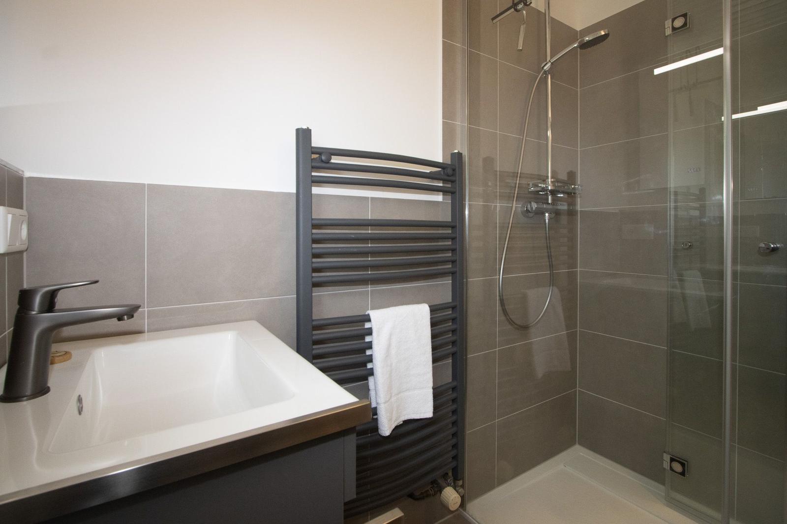 Bathroom with shower, sink, and towel rack