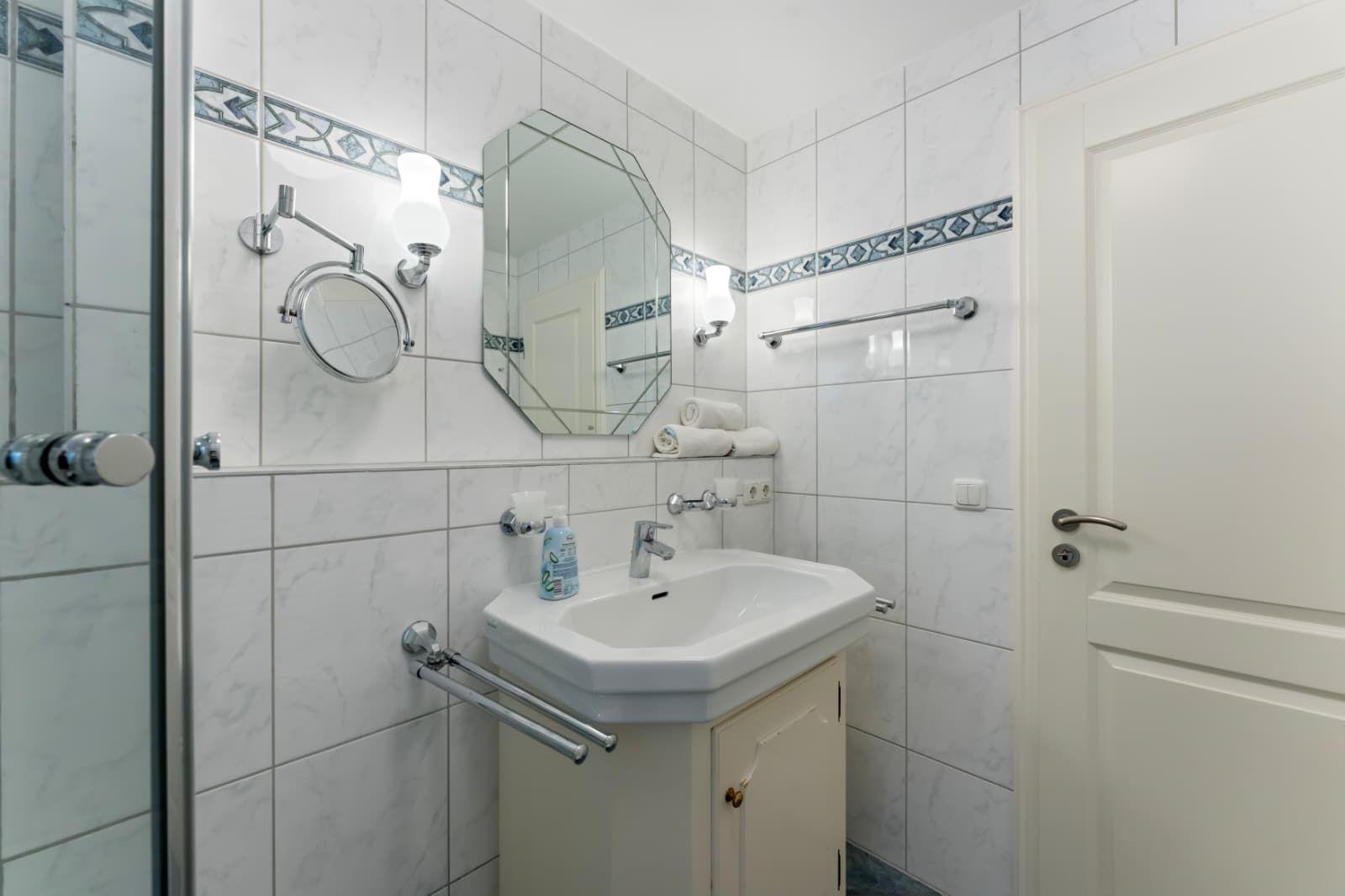 Badezimmer mit Waschbecken, Spiegel und Dusche