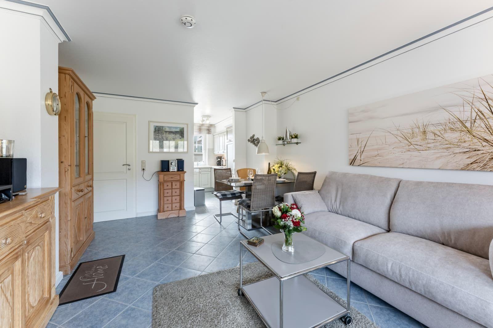 Wohn- und Essbereich mit Sofa, Tisch und Küchenbereich im Hintergrund.