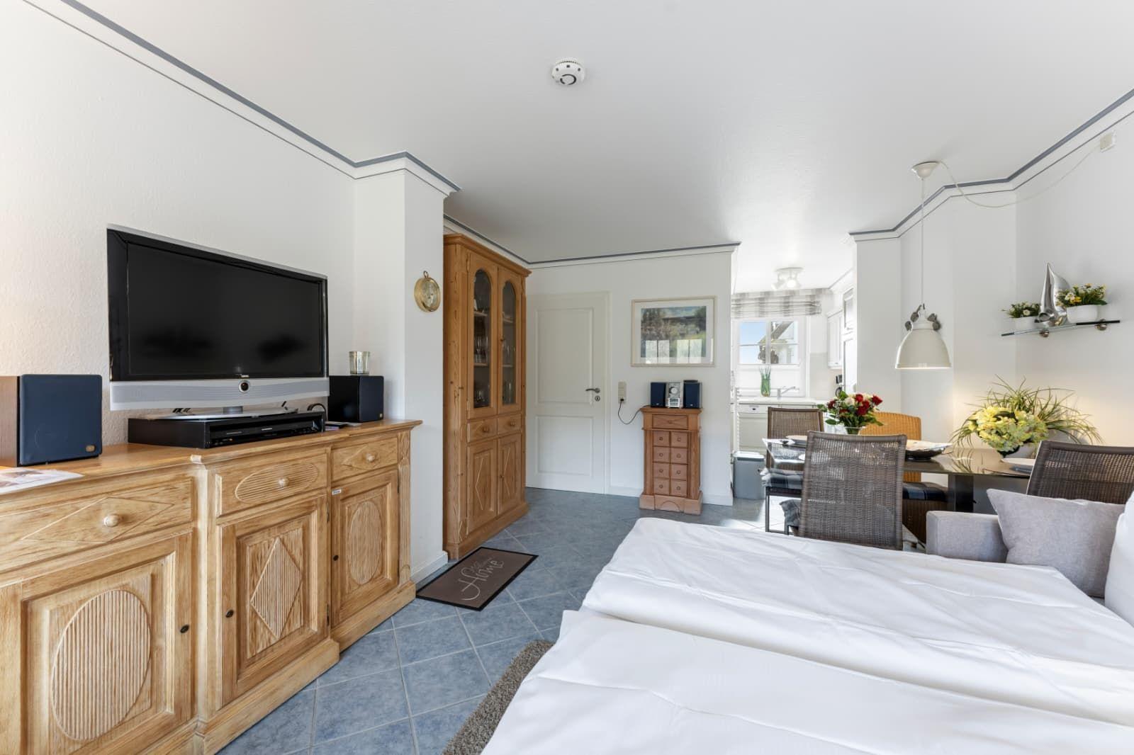 Schlafzimmer mit TV, Holzmöbel und Blick in Essbereich