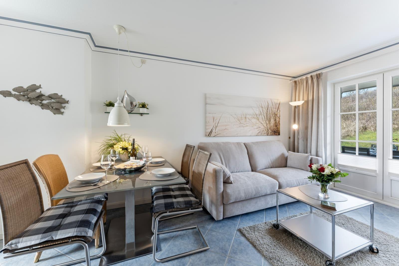 Wohn- und Essbereich mit Sofa, Esstisch und Fenster zur Außenterrasse.