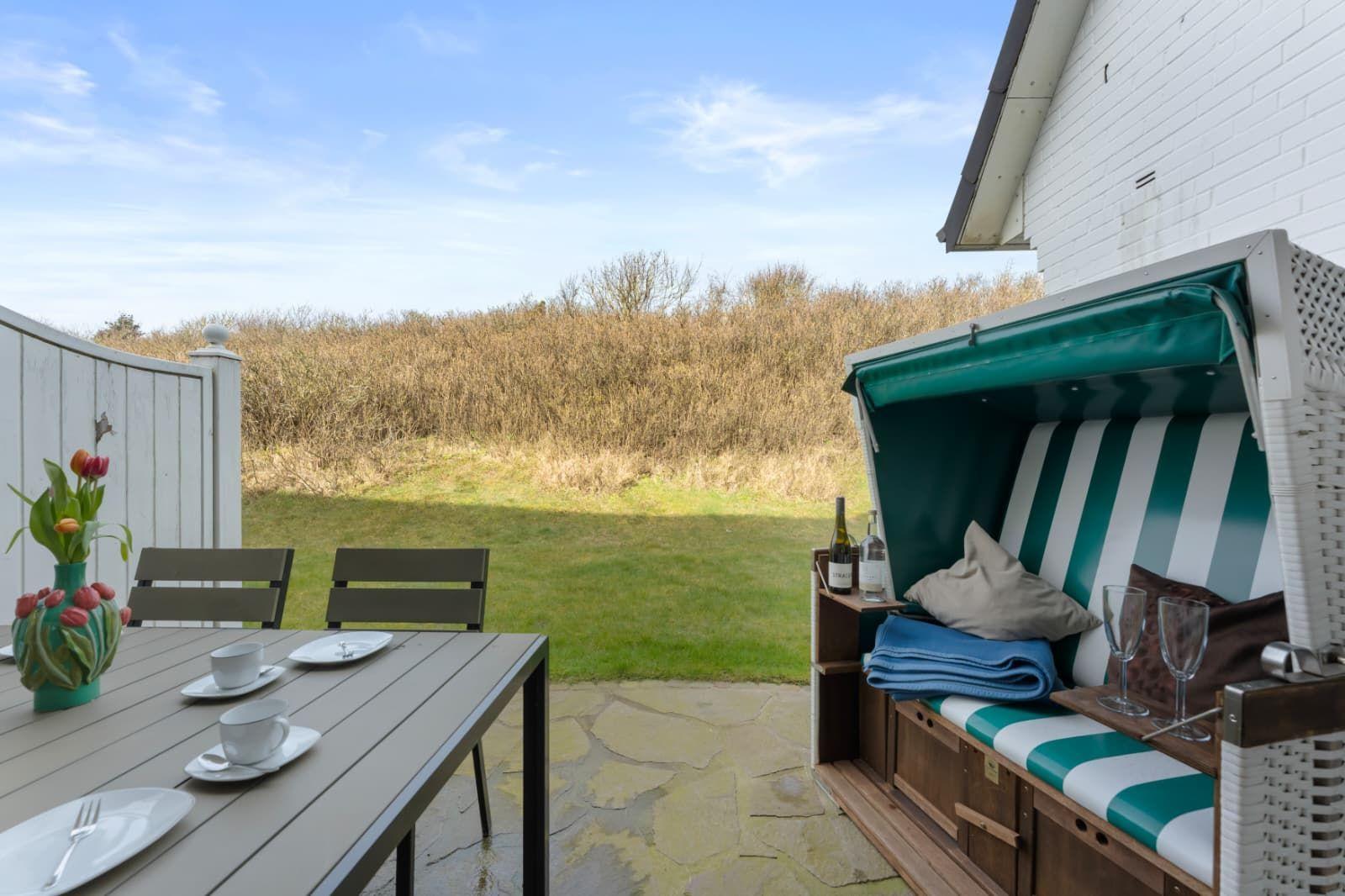 Terrace with table, chairs, and beach cabana with green-white stripes.