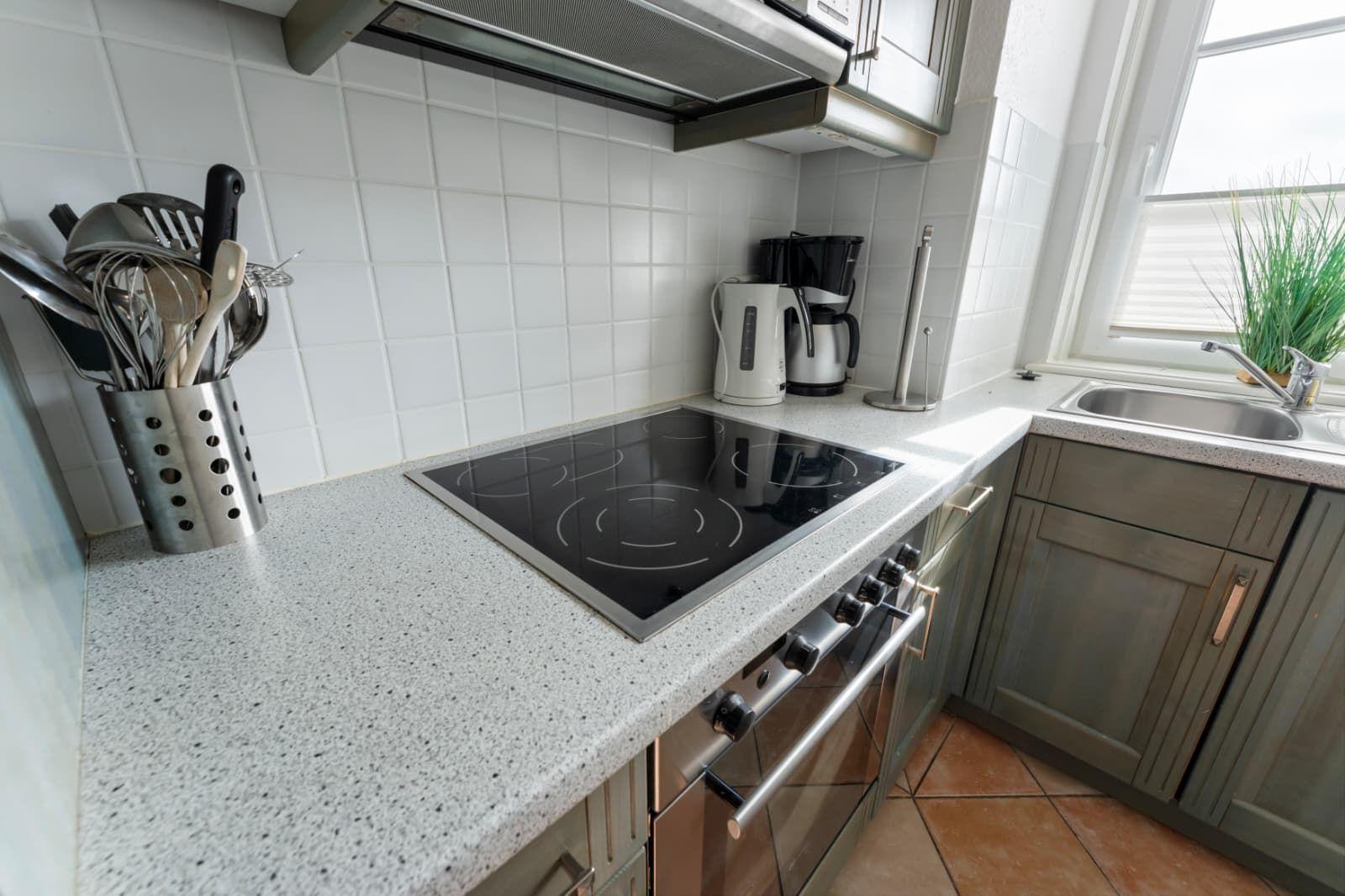 Kitchen with stove, sink, and kitchen utensils on the countertop.